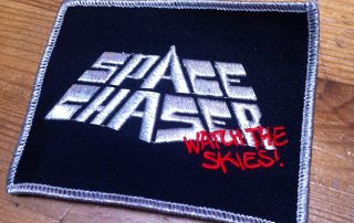 Space Chaser - Watch Patch <p>Macht sich mit feschem Silberfaden gut auf jeder Kutte!
100% Baumwolle - Grösse: 10x6 cm</p>